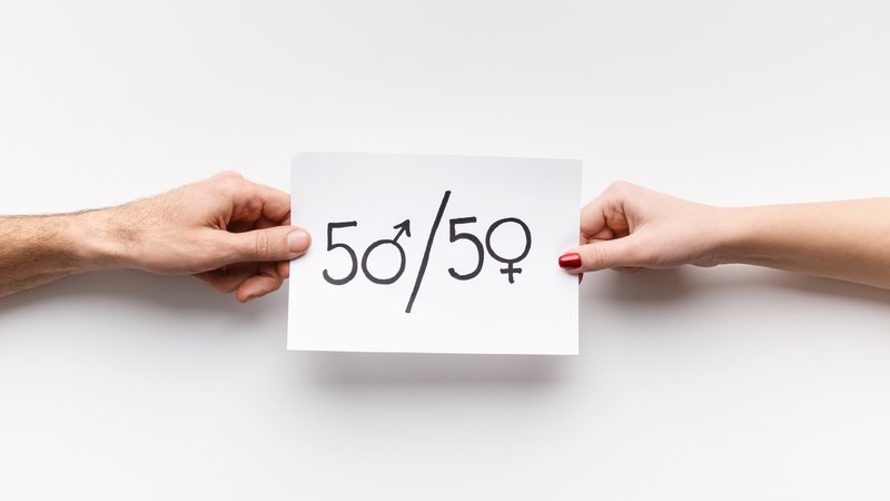 Frau und Mann halten weißen Zettel mit der Aufschrift "50/50"